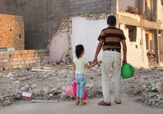 Image of young girl and her father looking at the rubble of the school.