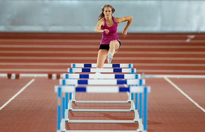 sports woman jumping over hurdles