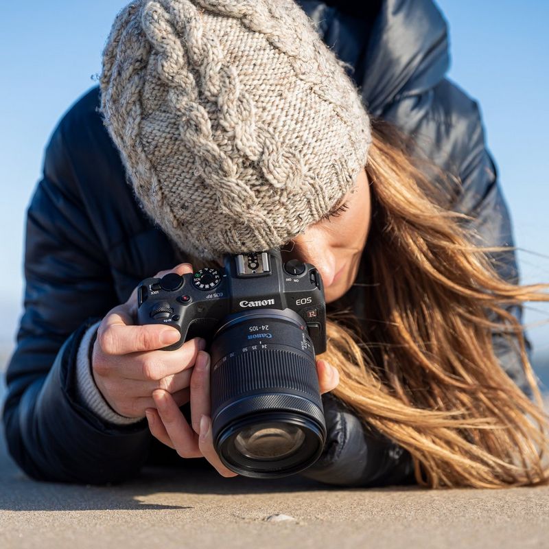 Lady wearing a grey beanie, blue coat and taking a shot on the EOS RP with RF 24-105mm F4-7.1 IS STM