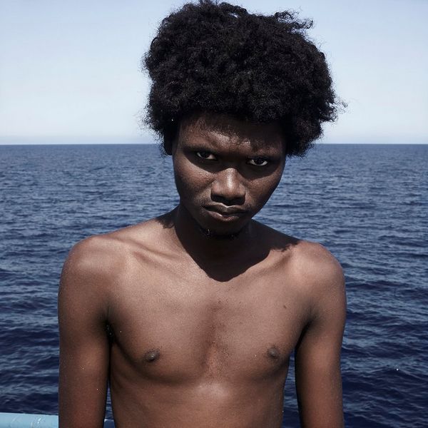 Topless teenager Alpha, aged 18, scowls at the camera after his rescue from the Mediterranean.