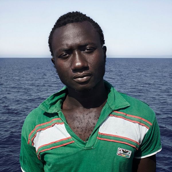 Enssa, aged 17, from Senegal, wears a emerald green tee-shirt aboard the Iuventa after coming aboard from the inflatable, black rubber rib he had been rescued from.