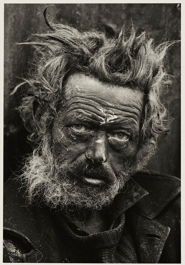 A homeless man from Ireland with bedraggled, grey hair sticking up in different directions, on the streets of the East End, London where he is living. 