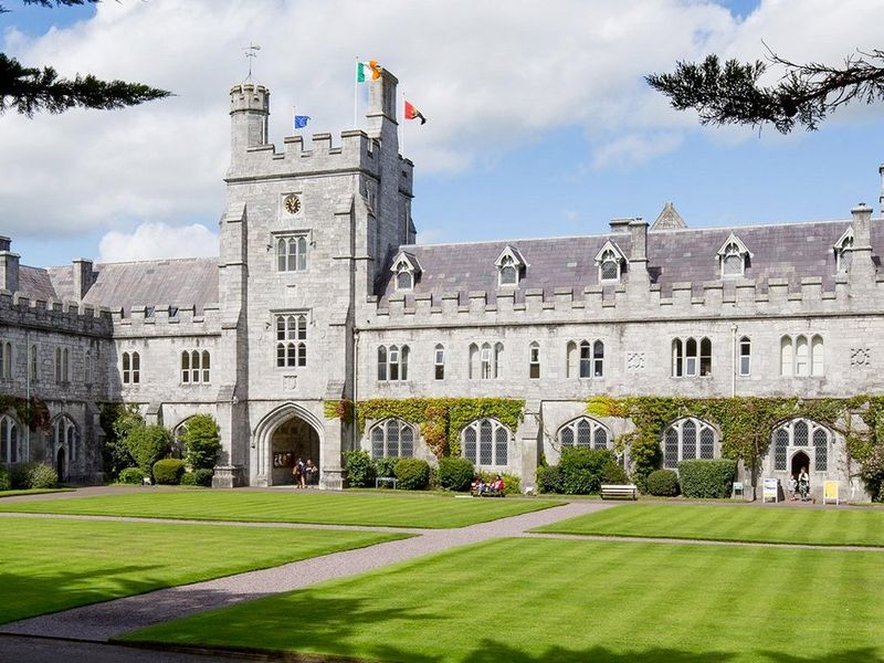 صورة بانورامية لمباني جامعة كورك University College Cork بأيرلندا في مقابل سماء زرقاء غائمة.