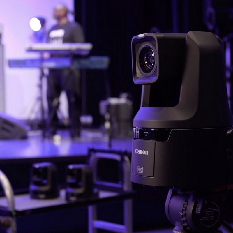A Canon CR-N500 PTZ camera set up to film a live music performance, with a keyboard player on stage in the background.
