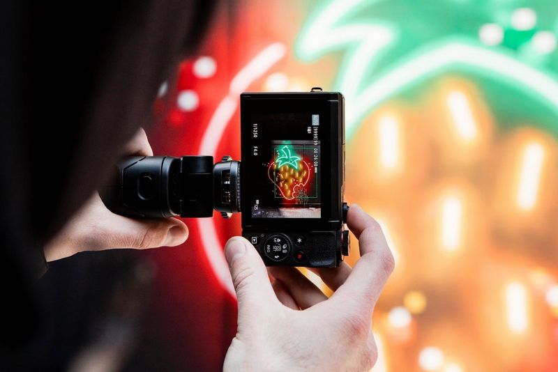 شخص يصوّر رسمة فراولة متوهجة مثل النيون على جدار باستخدام كاميرا PowerShot G7 X Mark III من Canon.