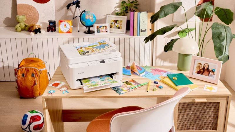 Canon Printer printing a colourful page on a child’s desk with school supplies and toys