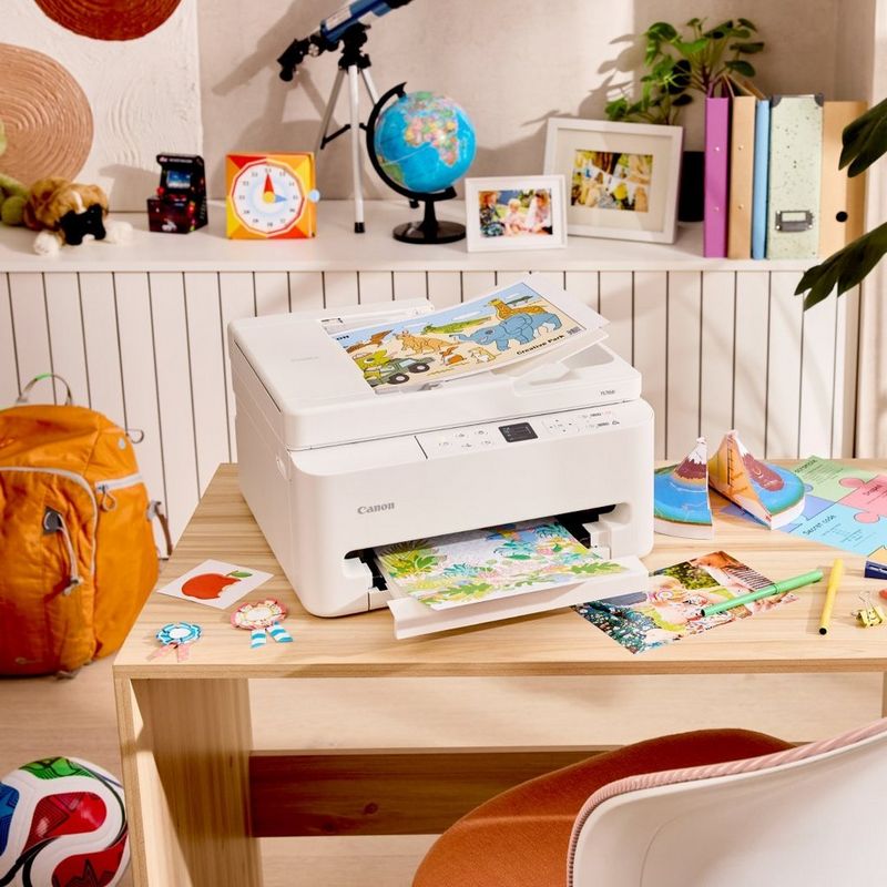 Canon Printer printing a colourful page on a child’s desk with school supplies and toys