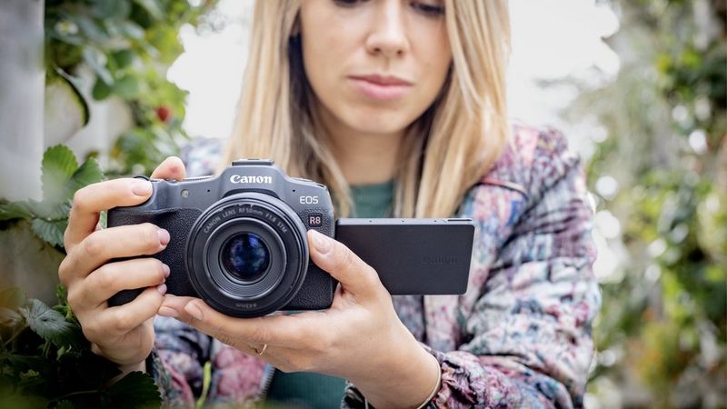 Fotógrafo utiliza la cámara mirrorless Canon EOS R8 para hacer una foto en un jardín.