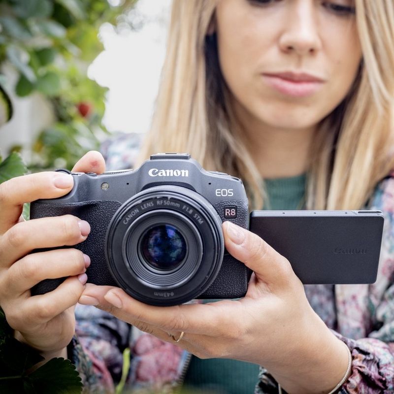 Fotógrafo utiliza la cámara mirrorless Canon EOS R8 para hacer una foto en un jardín.
