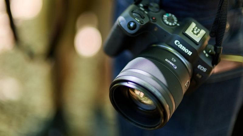 Canon mirrorless camera with a Canon RF 45mm F1.2 STM Lens hanging from a camera strap.