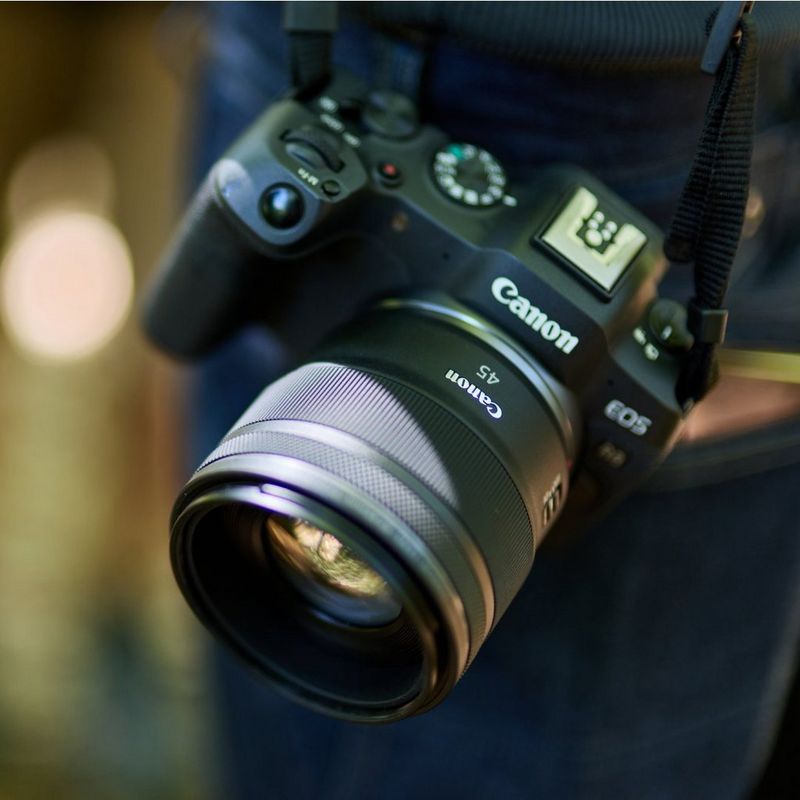 Canon mirrorless camera with a Canon RF 45mm F1.2 STM Lens hanging from a camera strap.