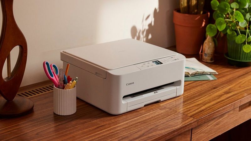 Kompakt PIXMA-printer i et hjemmekontor ved siden af kontorartikler og planter.
