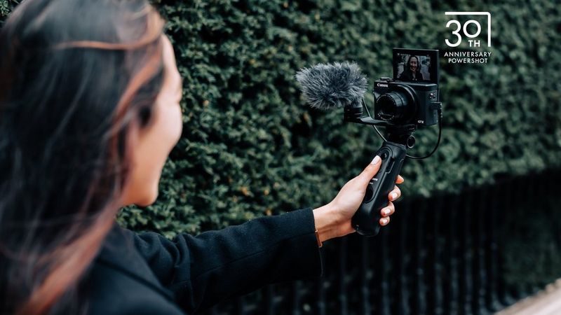 Une personne utilisant le Canon PowerShot G7 X Mark III sur un tripod grip pour filmer une vidéo.