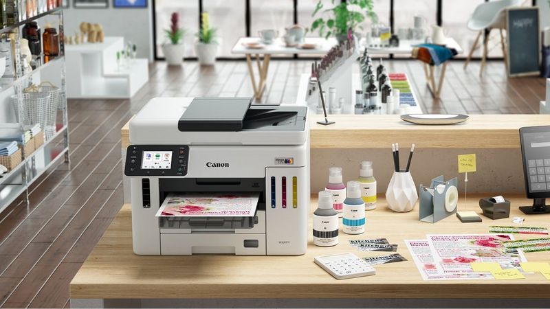 Canon MAXIFY GX7150 printer in a creative workspace printing colourful materials beside craft supplies.