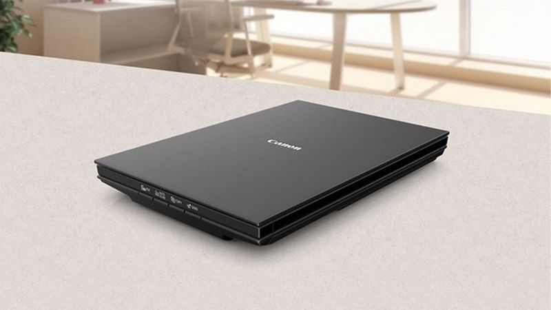 Canon CanoScan LiDE 300 flatbed scanner on a desk in a clean office workspace.