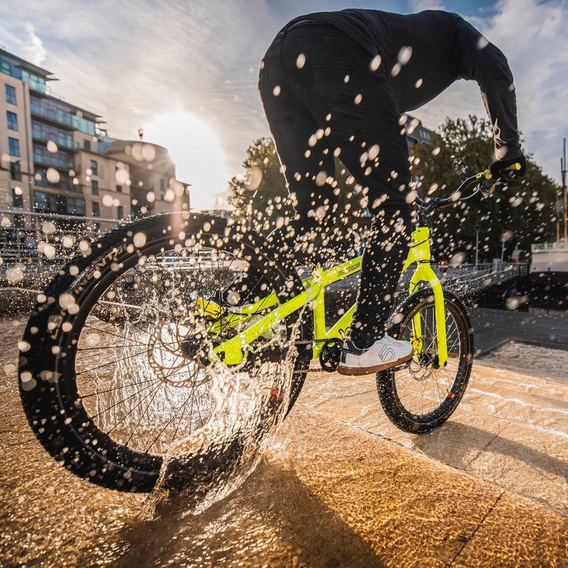 An action shot taken with a Canon Speedlite EL-1 shows a stunt rider cycling down stone steps, a spray of water droplets caught by the flash.