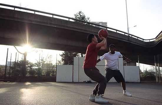 2 men playing basketball with sunlight behind them