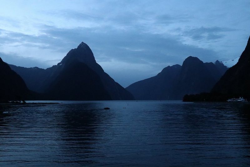 A large body of water surrounded by hills and mountains, in low light.