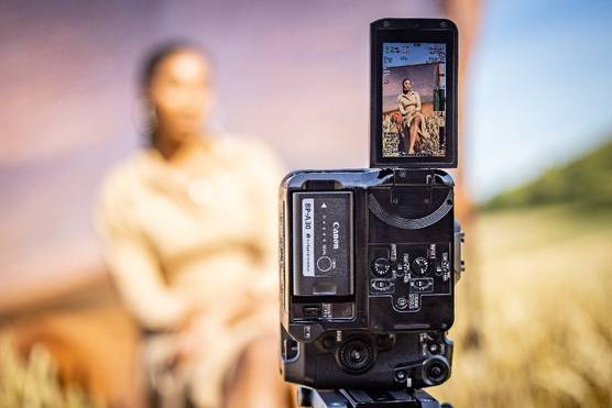 A Canon EOS C70 camera mounted vertically to film a seated woman in portrait mode.