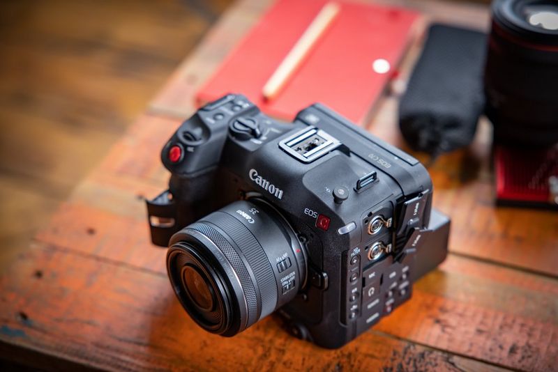 A Canon EOS C70 camera on a wooden desk taken from above. 