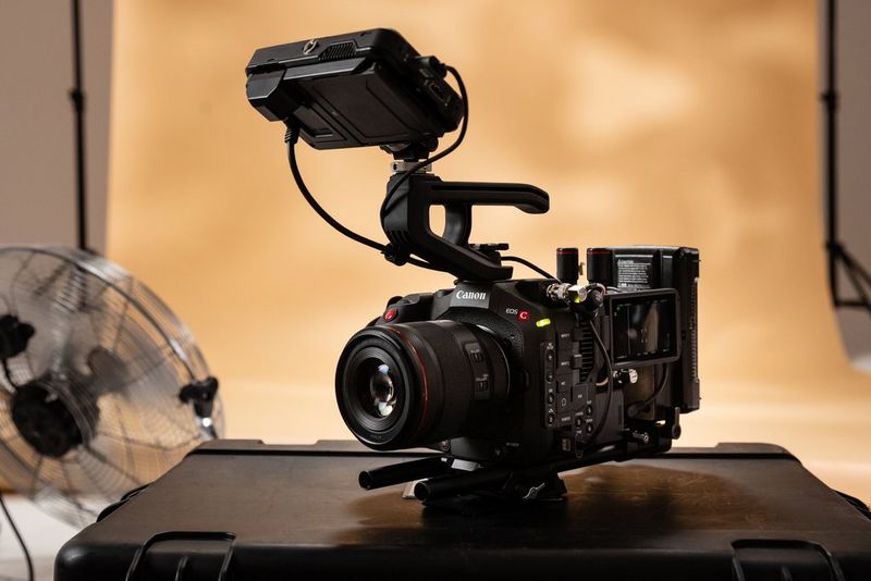 A Canon EOS C80 camera rests on top of a sleek black case in a film studio setting.