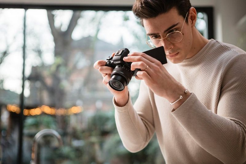 Мужчина пристально смотрит на экран камеры Canon EOS M50 Mark II.