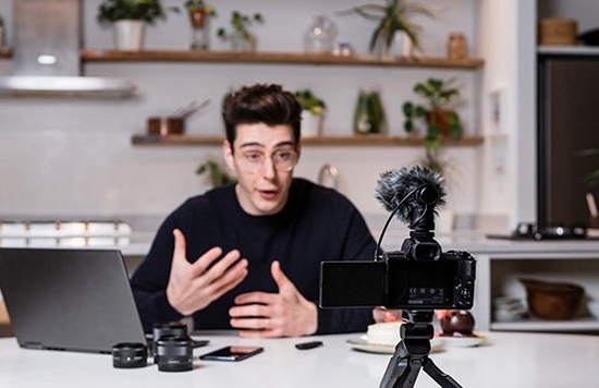 Vlogger Matt Adlard sat at a kitchen table filming a video on the EOS M50 Mark II.