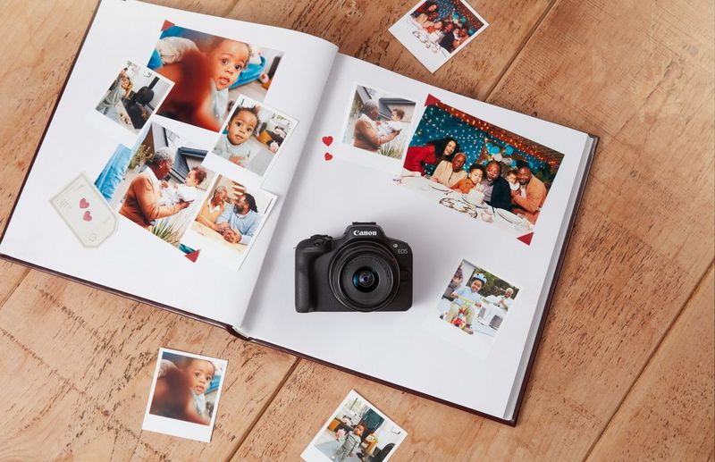 A Canon 澳门现金网_申博信用网-官网100 camera lies on a photo album on a wooden table, surrounded by family photographs.