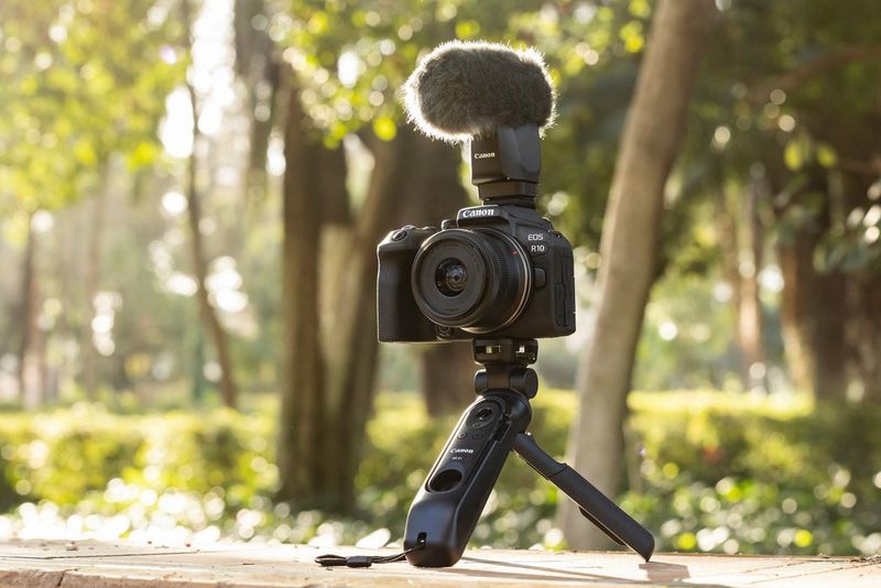 تم إعداد لقطة منتج خارجية لكاميرا EOS R10 من Canon، مع توصيل ميكروفون وحامل ثلاثي القوائم صغير لتسجيل الفيديو.