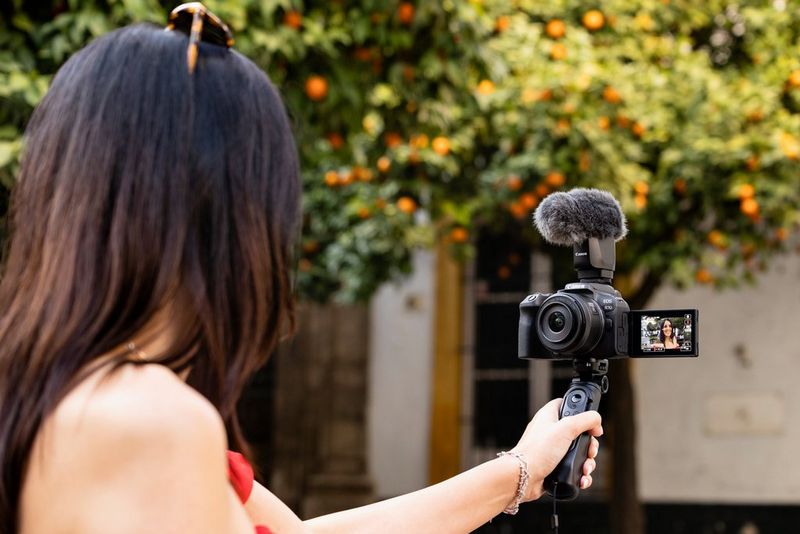 A person records themselves on a sunny day using a Canon EOS R10 camera and mic.