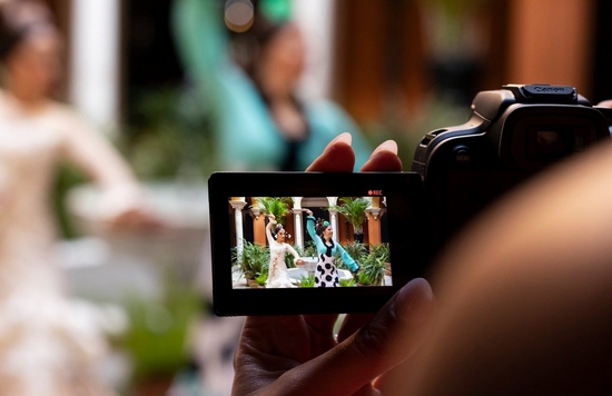 A view over the photographer's shoulder of the LCD screen of a Canon EOS R10, showing two flamenco dancers being filmed.