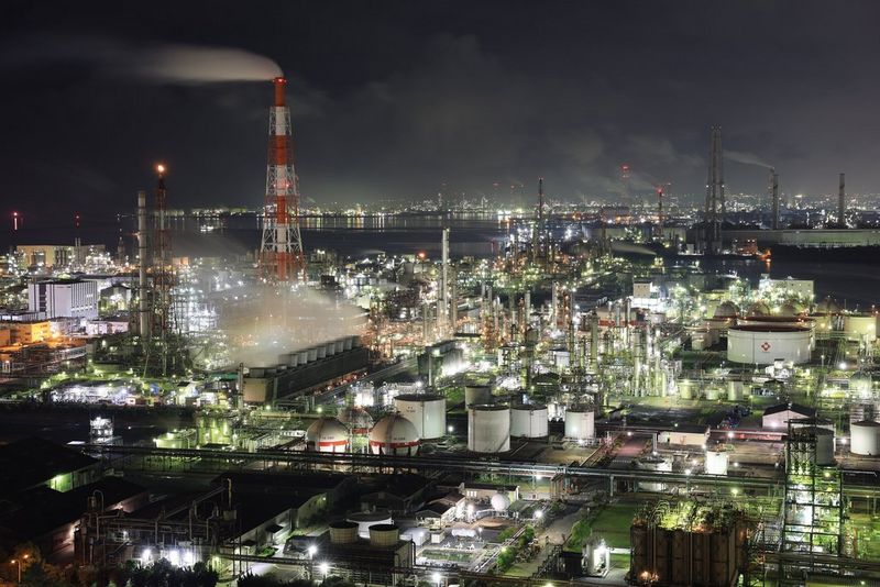 Un grande impianto industriale e i suoi dintorni di notte. L'impianto ha un'illuminazione potente e sullo sfondo si vede il profilo di una città. Scatto realizzato con Canon EOS R3.