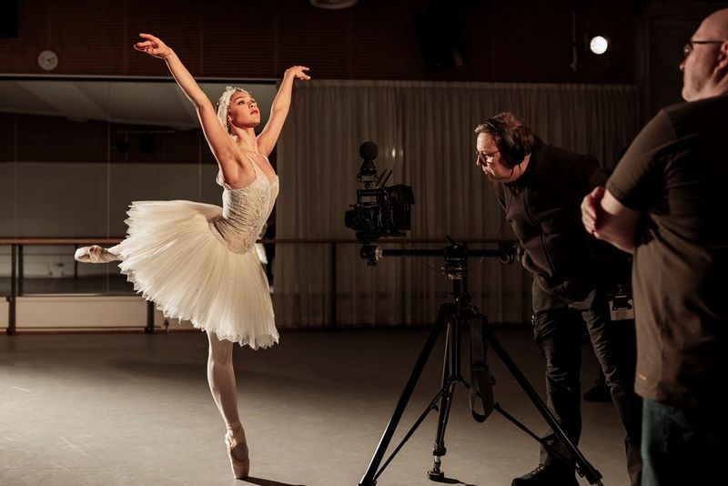 Clive Booth films a ballerina with one leg raised behind her and her arms outstretched on a Canon EOS R5 C camera with a Canon RF 5.2mm F2.8L DUAL FISHEYE lens.