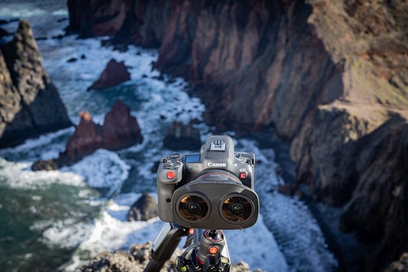 A Canon EOS R5 C, with a Canon RF 5.2mm F2.8L Dual Fisheye lens attached, mounted on a tripod and positioned on a cliff edge overlooking the sea. 