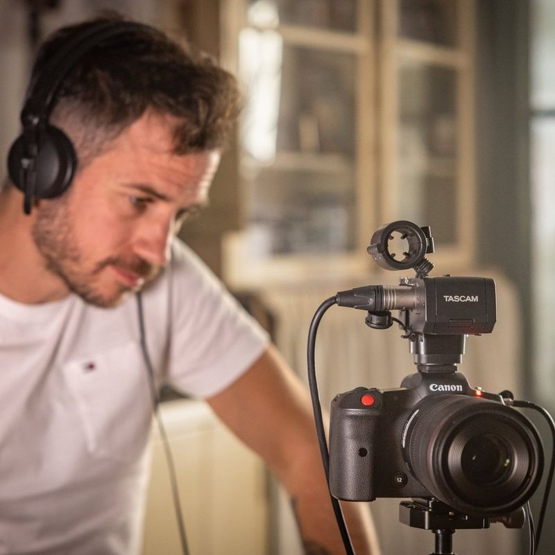 Filmmaker Kevin Clerc stares intently at the back of a Canon EOS R5 C camera set up on a tripod.