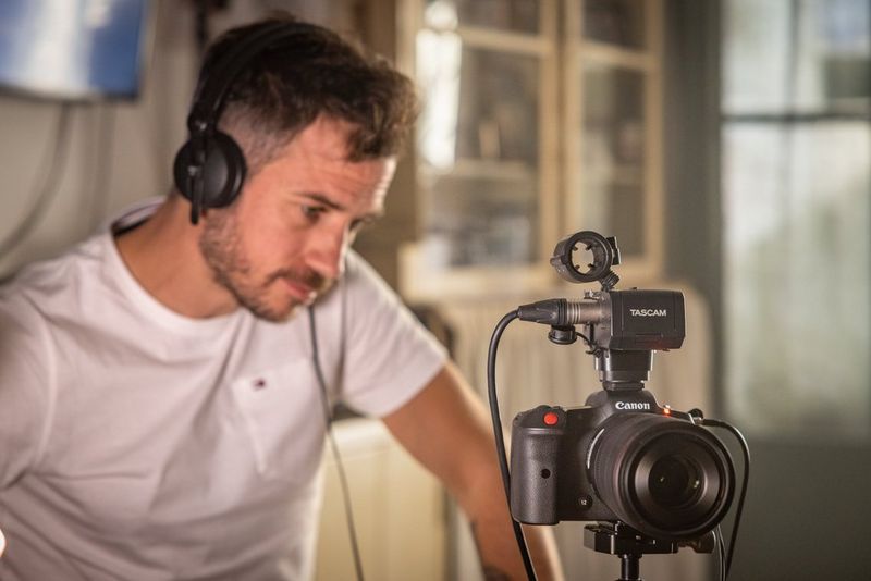 Filmmaker Kevin Clerc stares intently at the back of a Canon EOS R5 C camera set up on a tripod.