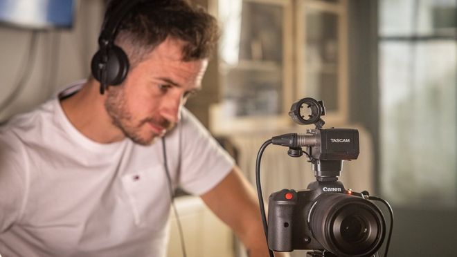Filmmaker Kevin Clerc staart geconcentreerd naar de achterkant van een Canon EOS R5 C-camera op een statief.