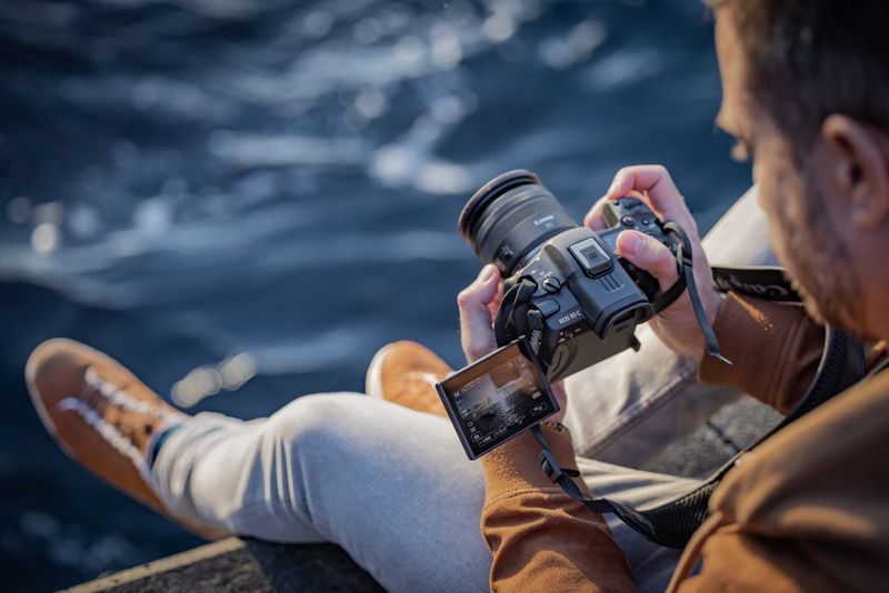 A man sitting on the edge of a boat filming with a Canon EOS R5 C camera.