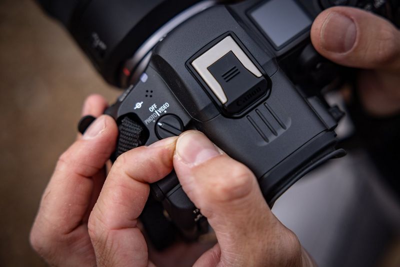 Fingers adjusting the Photo/Video switch on the top of a Canon EOS R5 C hybrid camera.