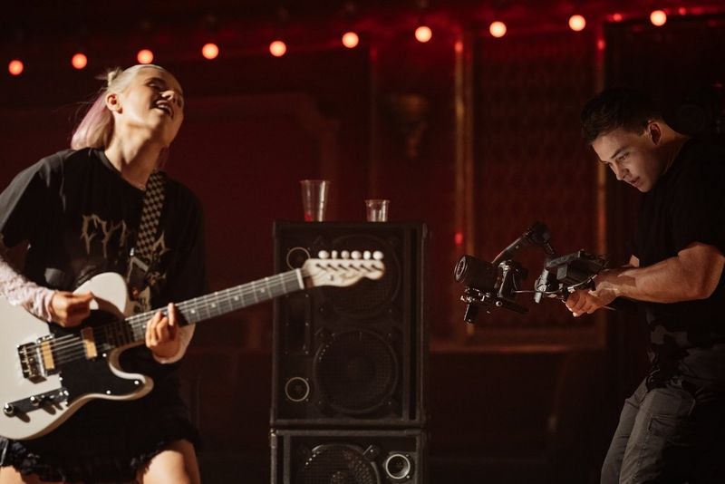 A filmmaker uses a Canon EOS R5 Mark II camera on a gimbal to film a guitarist performing.