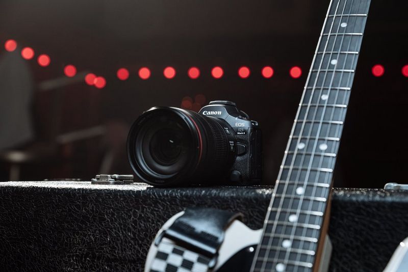 L'appareil photo Canon EOS R5 Mark II posé sur un caisson d'ampli avec une poignée de guitare à côté.