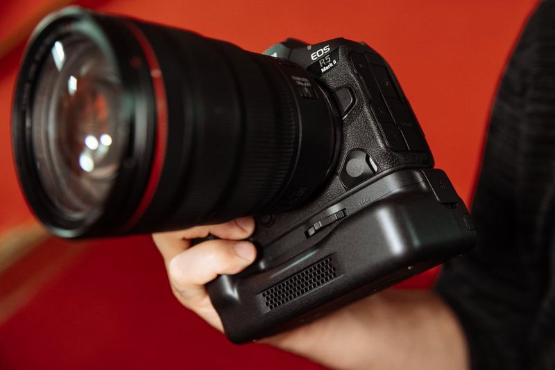  A user's hand holds a Canon EOS R5 Mark II camera with an optional Cooling Fan CF-20EP Grip fitted.