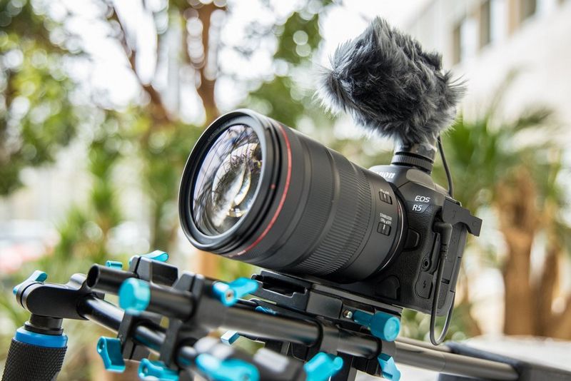 A Canon EOS R5 attached to a camera rig and with a microphone on top.