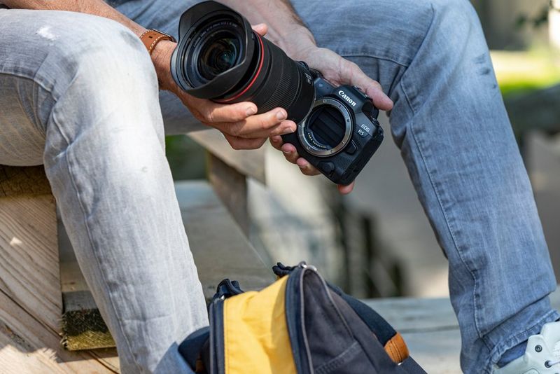 A filmmaker changing an RF lens on the Canon EOS R5. 