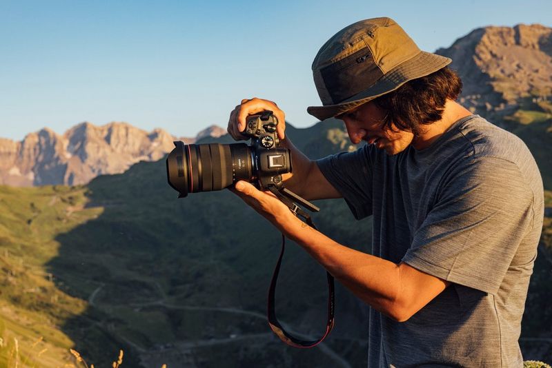 Teddy Morellec holding a Canon EOS R6 Mark II in front of him and looking down at the folded-out touchscreen.