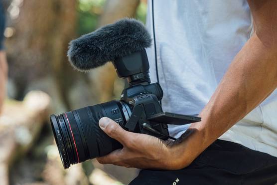 A close up of a person holding a Canon 中国福彩网6 Mark II camera in their left hand.