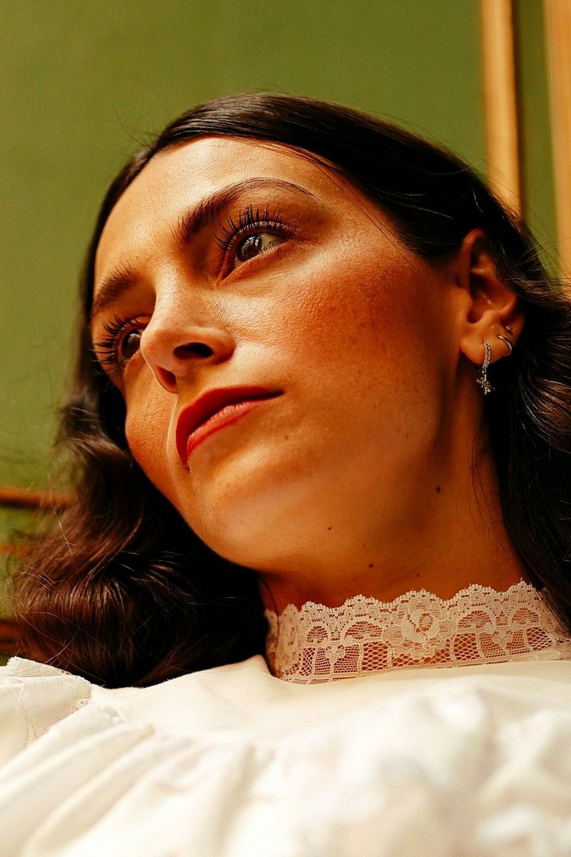 A close-up of a woman's face as she looks up and away from the camera.