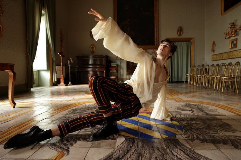 Ballet dancer Lee Jay Hoy poses on the floor of an ornately decorated room.