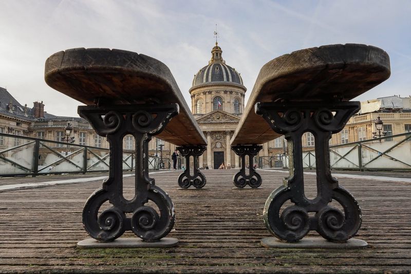 Снимок двух скамей возле Института Франции, сделанный на камеру Canon EOS R8 с низкого ракурса, вдалеке видно здание.