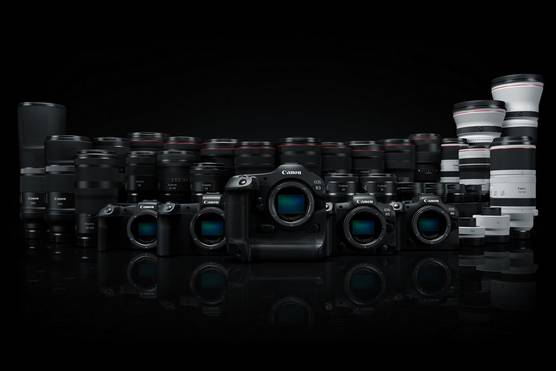 A row of Canon EOS R System cameras displayed in front of a row of RF lenses.
